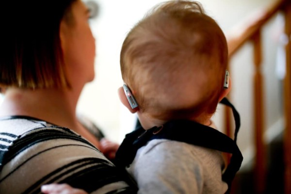 Mother holding baby with hearing aids