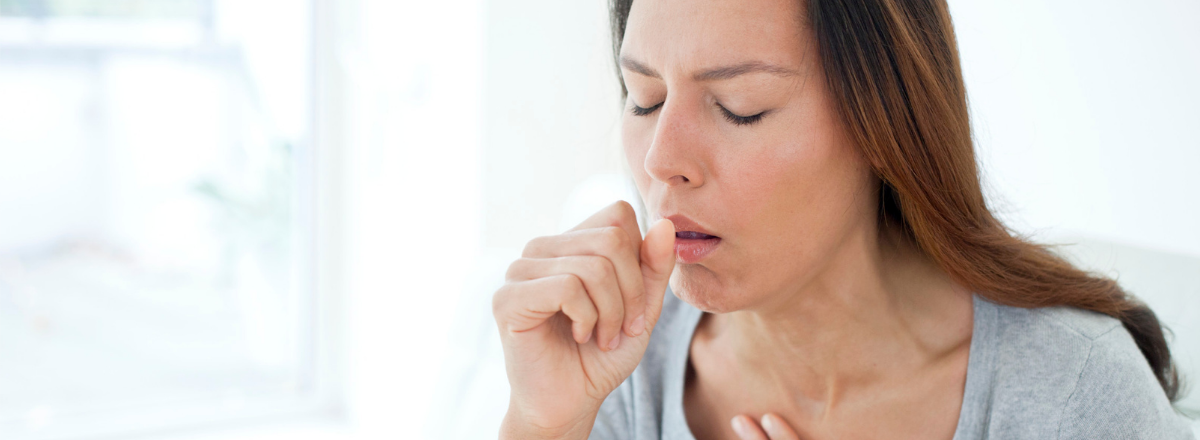 Image shows white female coughing into her hand.