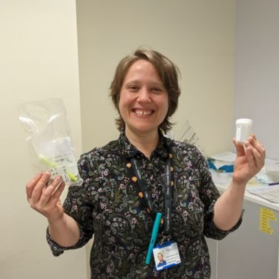 Image shows Dr Jen Davies-Oliveira holding urine testing kit