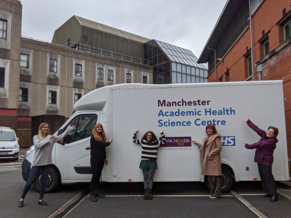 Two researchers, a mum and baby inside the research van